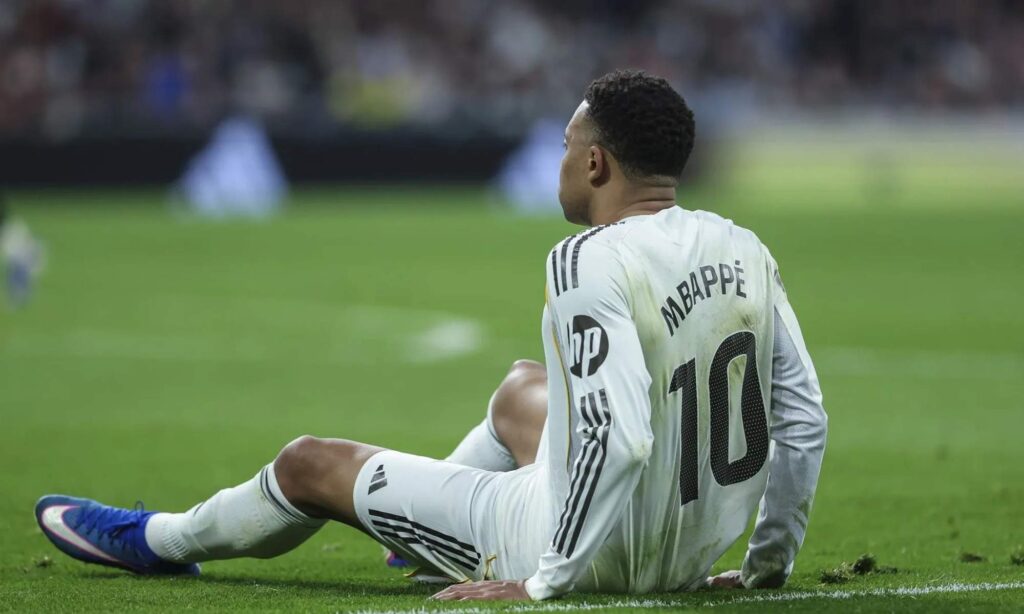 Kylian Mbappé, sentado en el césped en un partido del Real Madrid durante esta temporada.